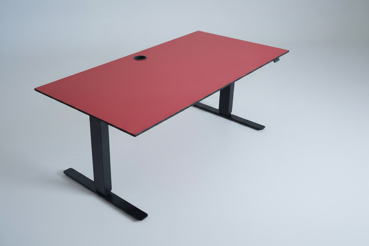 Martela hæve-sænkebord i rød linoleum 160x80 cm set fra skrå vinkel – ergonomisk skrivebord med affasede kanter og kabelbakke.